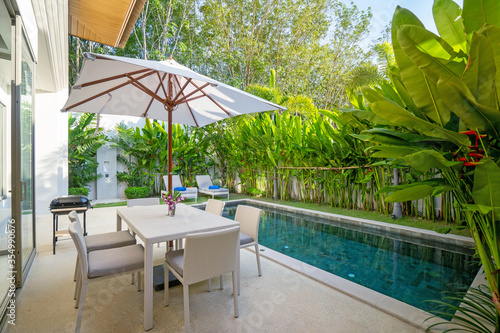 Exterior design in luxury pool villa feature pool terrace  garden landscape  outdoor dining table  BBQ  dining chair and umbrella