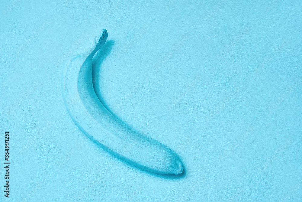blue painted banana on the background. creative design. copy space