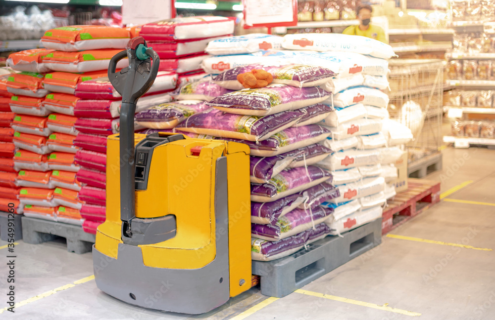 Fototapeta premium Hand pallet truck with the rice bag and plastic pallets with goods in the wholesale market.