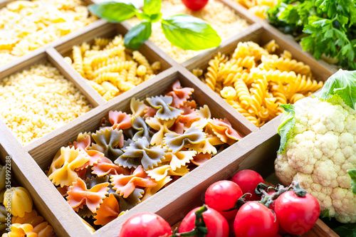 Different types of italian uncooked pasta in wooden box, whole wheat pasta, pasta, spaghetti, noodles, tagliatelle. Top view.