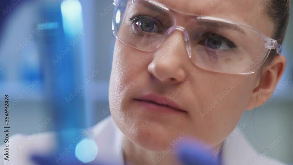 A female medical scientist works in a laboratory. Spcialist conducts experiments with fluids in test tubes, develops auccin auctin from the virus. Coronavirus covid-19. A female medical scientist works in a laboratory. Spcialist conducts experiments with fluids in test tubes, develops auccin auctin from the virus. Coronavirus covid-19.