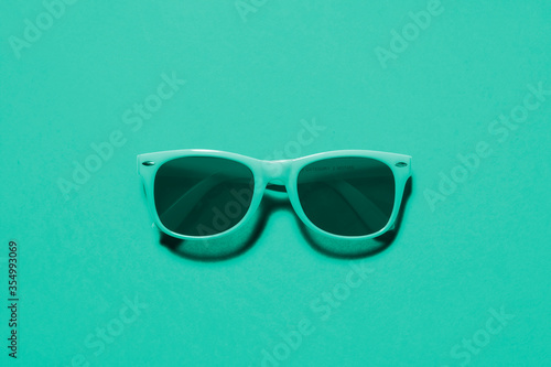Teal / cyan sunglasses top view / flat lay on a matching teal / cyan background with a centre composition