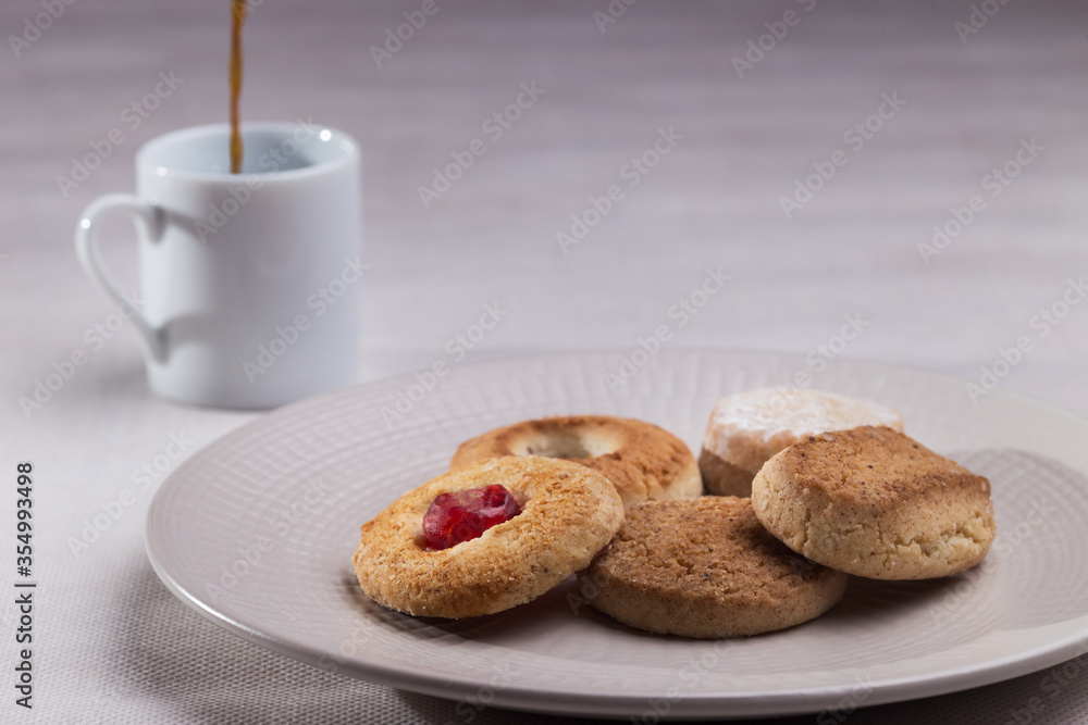 Cookies in dish and pouring coffee in white cup