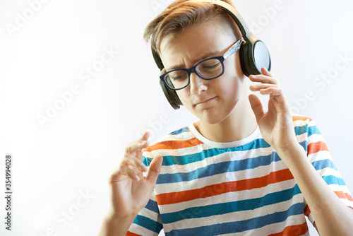 Funny boy teenager listens to music on headphones and dances
