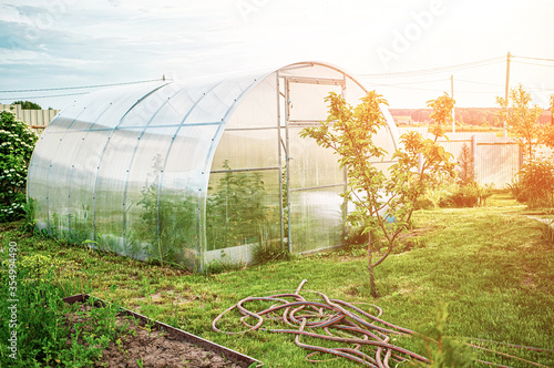 A polycarbonate greenhouse on a dacha plot on a Sunny day in spring photo