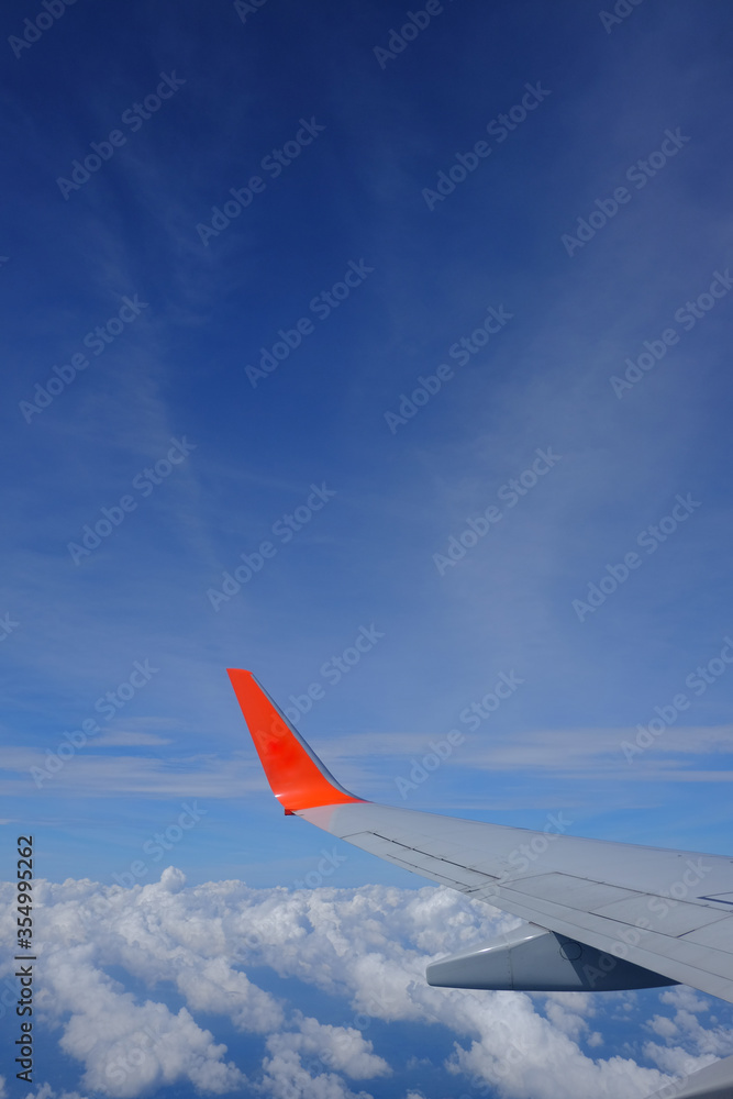 Wing of airplane with beautiful blue sky and clouds from airplane window, traveling  to oversea