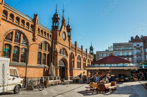 Old town market - people buying goods next to the brick building. Gdansk, Poland