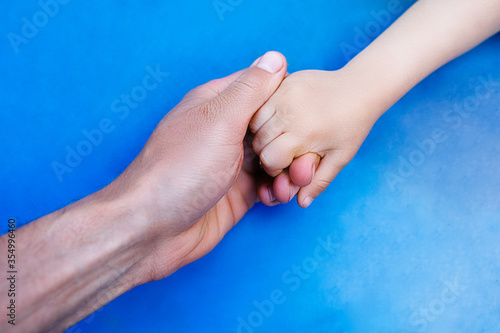 Father holding a hand of her daughter isolated on blue background