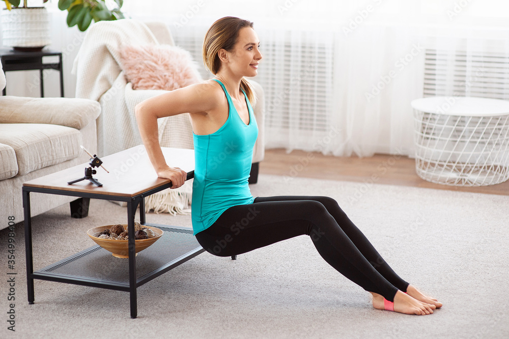 Fitness woman doing push-up exercise and watching online workout session on smartphone, training in living room Fitness woman doing push-up exercise and watching online workout session on smartphone, training in living room