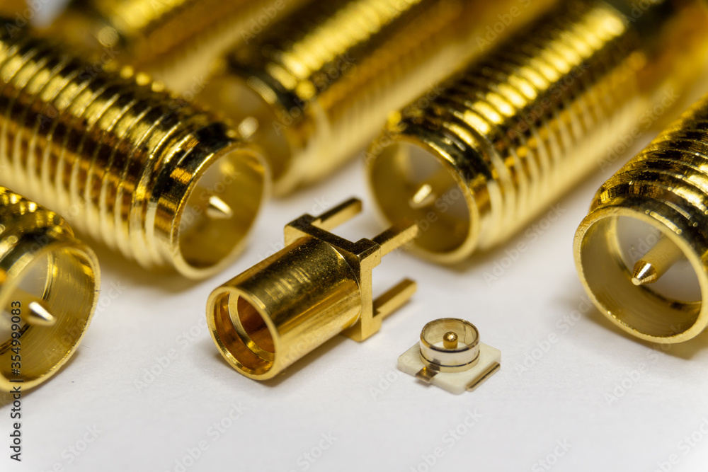 Close-up of symmetric aligned gold plated uFL, MMCX micro precision radio connector partial focus white SMA background Close-up of symmetric aligned gold plated uFL, MMCX micro precision radio connector partial focus white SMA background
