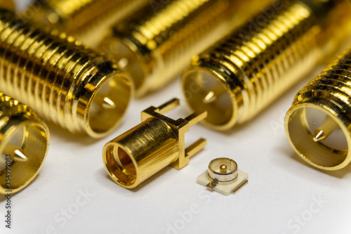 Close-up of symmetric aligned gold plated uFL, MMCX micro precision radio connector partial focus white SMA background