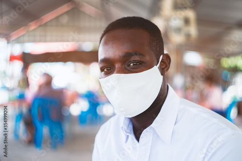 African man wear white shirt and face mask for virus protection with text Pray for the World corona virus or covid-19 in restaurant