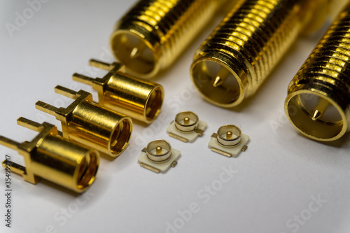 Close-up of symmetric aligned gold plated uFL, MMCX micro precision radio connector partial focus white SMA background