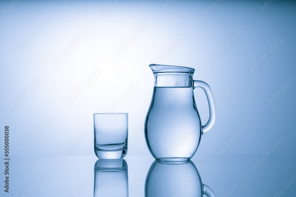 Pitcher with drinking water and a glass with a drink, blue tone Pitcher with drinking water and a glass with a drink, blue tone
