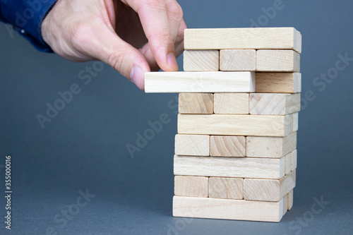 A tower of wooden blocks and a male hand occupy one block. Growth concept.