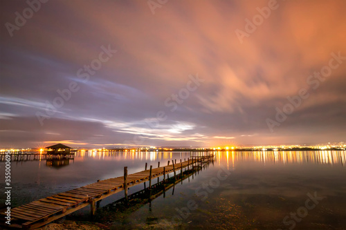 Beautiful night reflections in the sea from the port and moving clouds