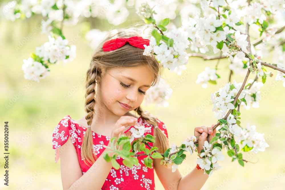 girl in a red sundress in a blooming garden girl in a red sundress in a blooming garden