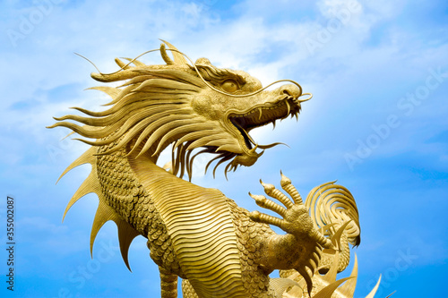 Golden dragon statue in blue sky background