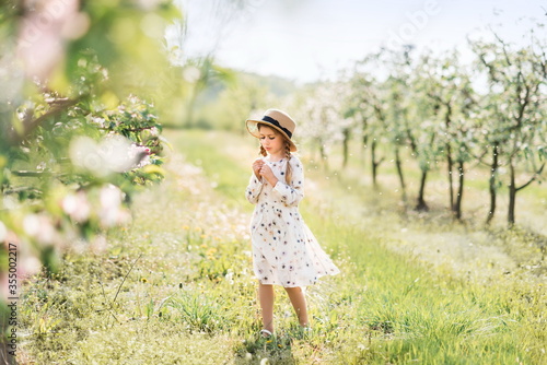 beautiful girl in the spring garden with dandelions. A summer hat and a light dress on it