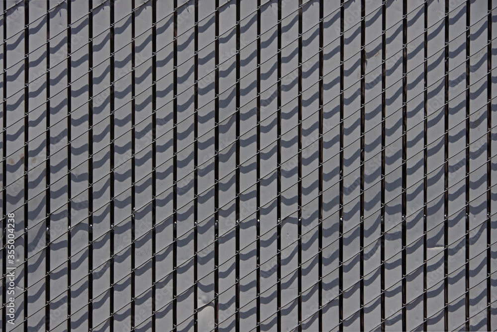 Close-up full frame view of a section of a chainlink fence filled with vertical gray slats Close-up full frame view of a section of a chainlink fence filled with vertical gray slats