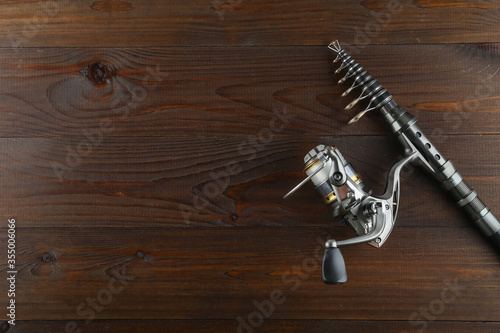 silver fishing reel and rod top view on a wooden background with copy space