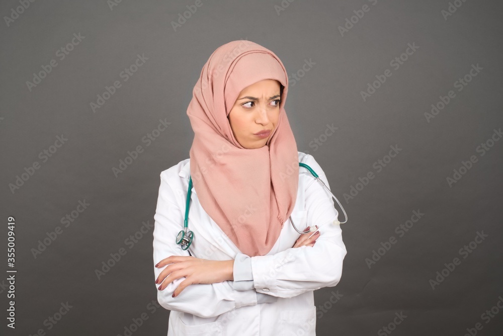 Closeup portrait displeased pissed off angry grumpy pessimistic muslim doctor woman with bad attitude, arms crossed looking sideways. Negative human emotion facial expression feelings Closeup portrait displeased pissed off angry grumpy pessimistic muslim doctor woman with bad attitude, arms crossed looking sideways. Negative human emotion facial expression feelings