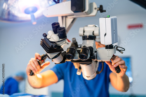 Modern microscope for operations in surgery room. Group of surgeons using operating microscope during their work photo