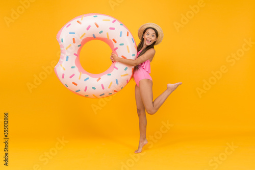 Accessories for swimming. Kid in swimsuit having fun. Summer vacation. Swimming and sunbathing. Safety on water. Safety measures around pool to keep bathers safe. Little girl and swimming donut ring photo