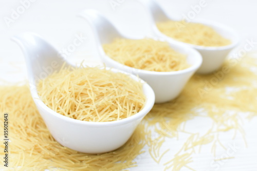 Short pasta spaghetti angel hair displayed in containers on white background