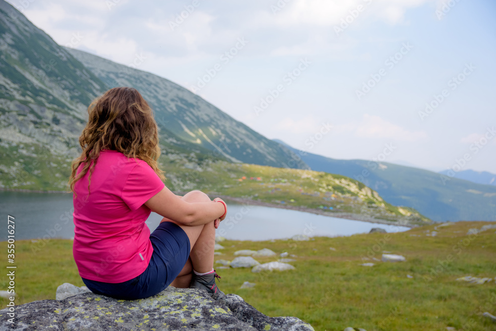 Young girl with colored shirt and wavy hair looking over glaciar lake in Carpathians mountains in Romania Young girl with colored shirt and wavy hair looking over glaciar lake in Carpathians mountains in Romania