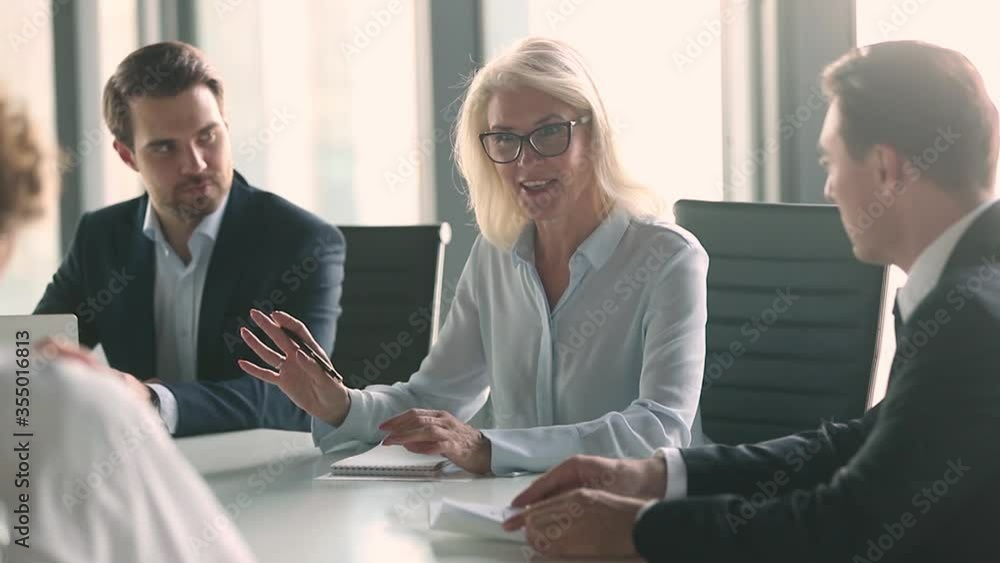 Business meeting lead by middle aged woman in modern boardroom, business parties company representatives meet for plan future collaboration, discuss terms conditions sign contract solve issues concept Business meeting lead by middle aged woman in modern boardroom, business parties company representatives meet for plan future collaboration, discuss terms conditions sign contract solve issues concept