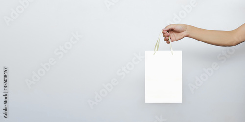 Hands hold a paper bag for online food and grocery delivery on a white isolated background with a copy of the space. Concept of the courier business of buying and ordering