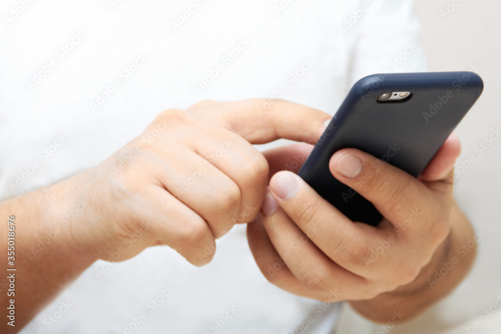A person is holding a phone and tapping the screen on a white background with copy space. Concept of lifestyle business and Internet technologies in the office A person is holding a phone and tapping the screen on a white background with copy space. Concept of lifestyle business and Internet technologies in the office