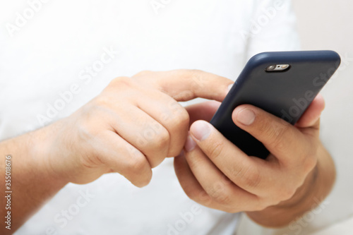 A person is holding a phone and tapping the screen on a white background with copy space. Concept of lifestyle business and Internet technologies in the office