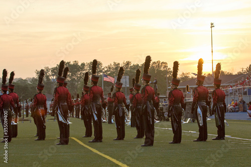 Marching band on a field at sunset. Marching in a line with trumpets and other instruments playing music. 