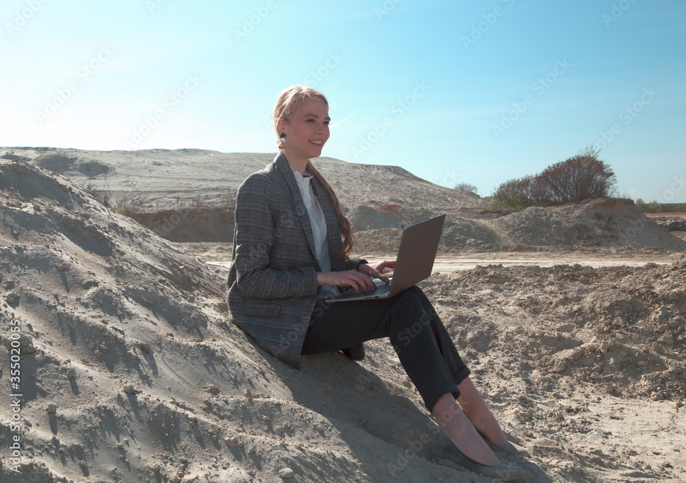 freelance and remote work.business woman in stylish business suit with laptop sitting in desert sand. Female student online training education abroad