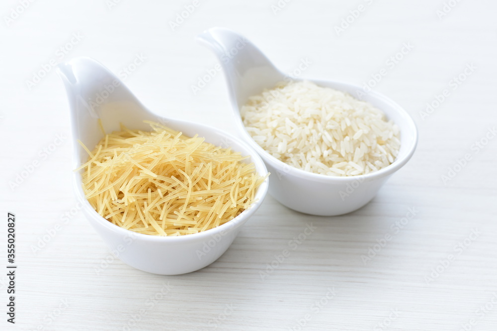 Short pasta spaghetti angel hair and uncooked rice displayed in containers on white background