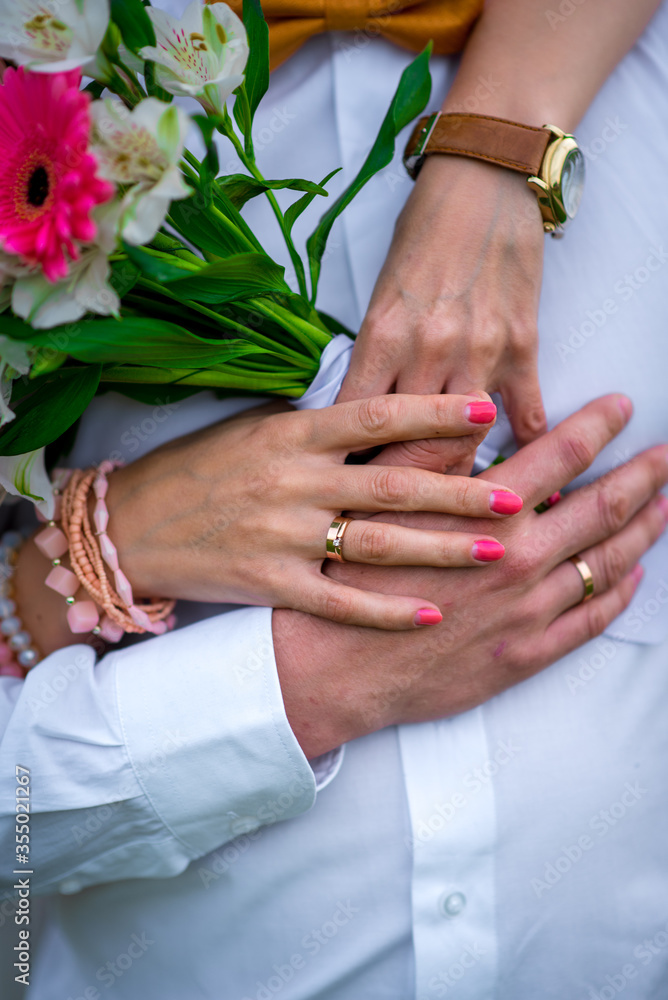 Beautiful and sophisticated wedding bouquet close-up holds the bride in her hands next to the groom. Wedding bouquet, and rings Beautiful and sophisticated wedding bouquet close-up holds the bride in her hands next to the groom. Wedding bouquet, and rings
