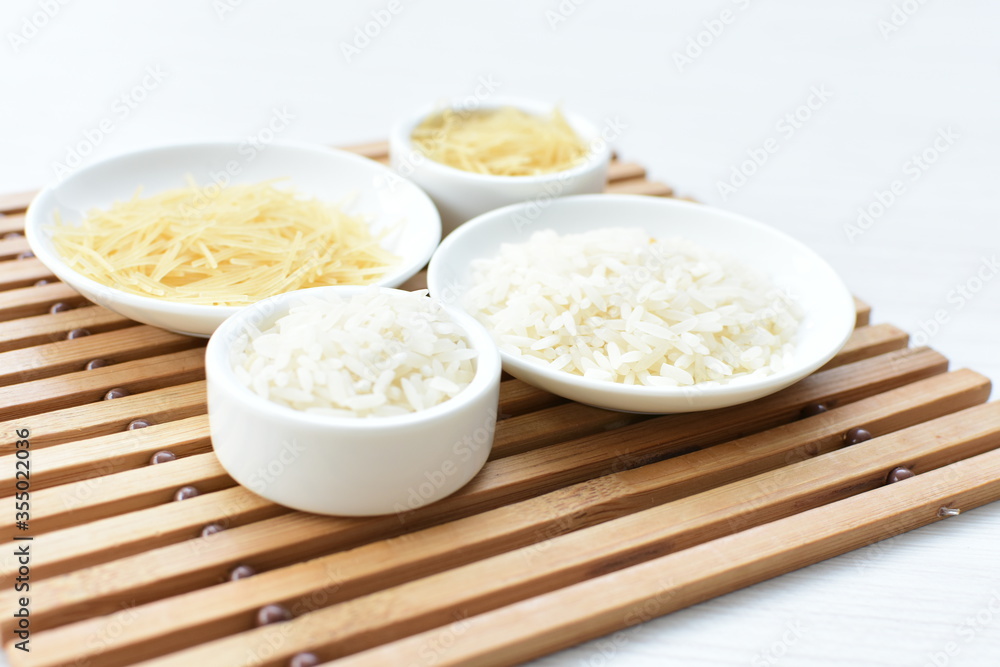 Short pasta spaghetti angel hair and uncooked rice displayed in containers on white background Short pasta spaghetti angel hair and uncooked rice displayed in containers on white background