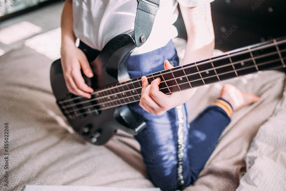 close up on the fingers of young girl playing bass guitar