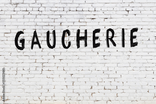 Word gaucherie painted on white brick wall photo