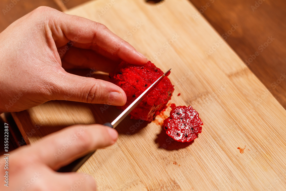 Cortando pitaya en tabla de madera con pequeño cuchillo Cortando pitaya en tabla de madera con pequeño cuchillo