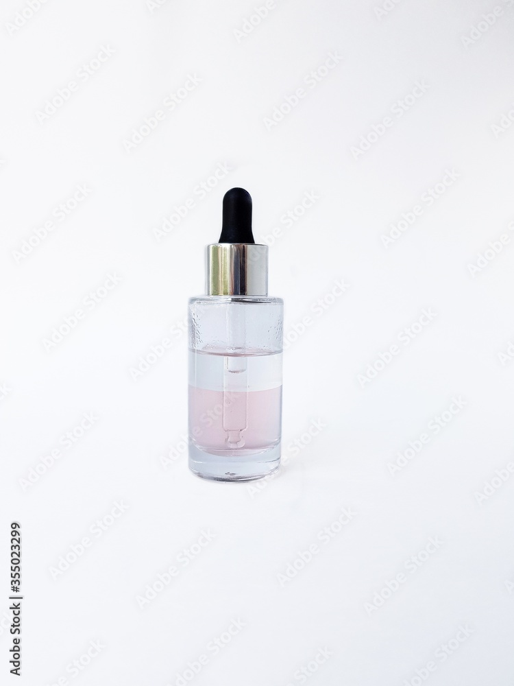 Cosmetic glass bottle with liquid inside and pipette, black rubber cap on a white background close-up. Cosmetic glass bottle with liquid inside and pipette, black rubber cap on a white background close-up.