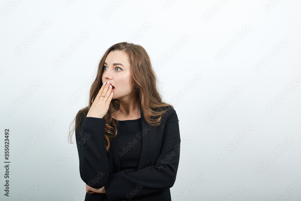 Shocked and speechless young female covering her mouth by hands. Young attractive woman brunette in a black t-shirt, sweater on white background Shocked and speechless young female covering her mouth by hands. Young attractive woman brunette in a black t-shirt, sweater on white background