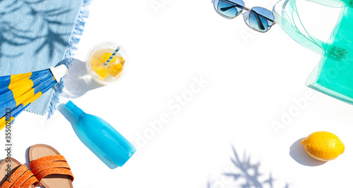 Bright summer vacation or travel lifestyle concept banner with flip flops, a beach bag, lemonade and sunscreen spray. Top view. Copy space