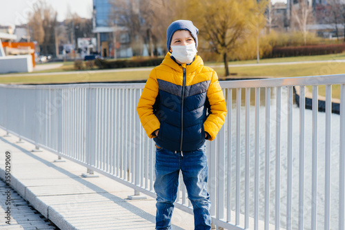 A boy stands on a gray background in a mask during a quarantine with free space. Quarantine in the mask