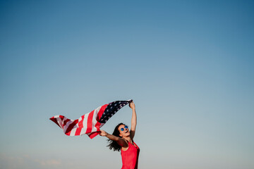 young woman holding United States flag outdoors at sunset. Independence day in America, 4th July concept
