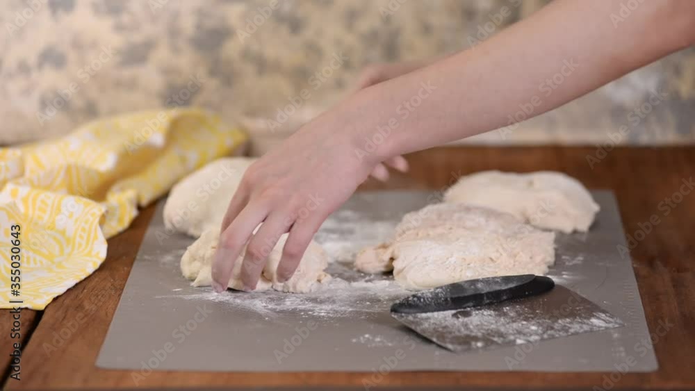 Female hands cut with a scraper a kneaded dough on working surface. Female hands cut with a scraper a kneaded dough on working surface.