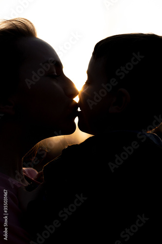 Silhouette of a mother and son playing outdoors at sunset. Mother's day concept