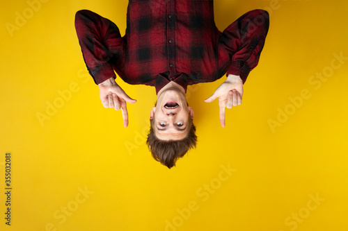 shocked guy with a funny hairstyle shows down on a copy space on a yellow isolated background © Богдан Маліцький